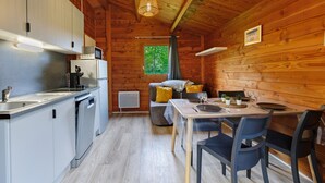 Een houten chalet van binnen, met een keuken, een eethoek en een raam met uitzicht.