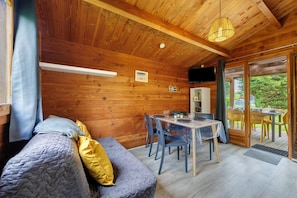Un intérieur en bois comprenant un canapé, une table à manger, des chaises et un téléviseur.