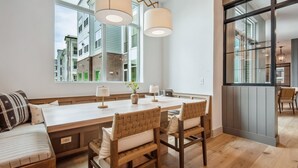 Una cocina moderna con una isla grande, sillas de madera y vistas a edificios cercanos.