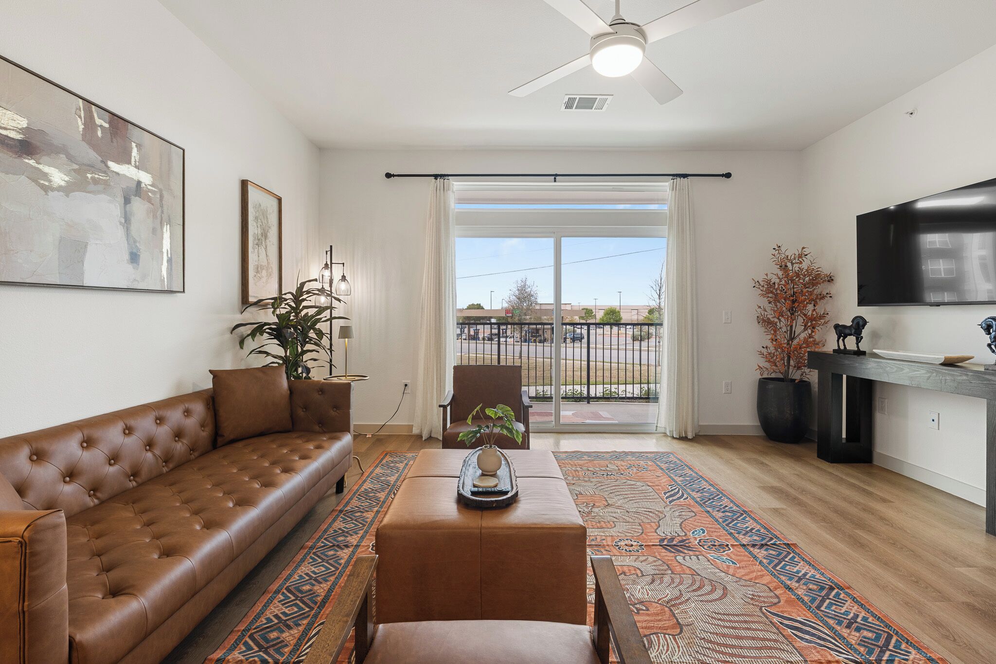 A living room with a sofa, ottoman, and a large window.