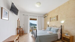 A bedroom with a bed, a desk, a chair, a TV, and a balcony with a view. - Studio Apartment 'With Seaview 1' with Sea View, Wi-Fi and Air Conditioning (Limni)