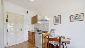A kitchen with a dishwasher, wooden cabinets, a white countertop, and a table with a placemat. - Studio Apartment 'With Seaview 1' with Sea View, Wi-Fi and Air Conditioning (Limni)