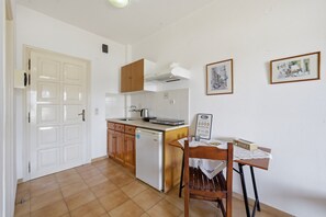 A kitchen with a dishwasher, wooden cabinets, a white countertop, and a table with a placemat. - Studio Apartment 'With Seaview 1' with Sea View, Wi-Fi and Air Conditioning (Limni)