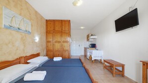 A hotel room with two beds, wooden cabinets, a television, and a small table. - Studio 'Garden View 4' with Sea View, Wi-Fi and Air Conditioning (Limni)