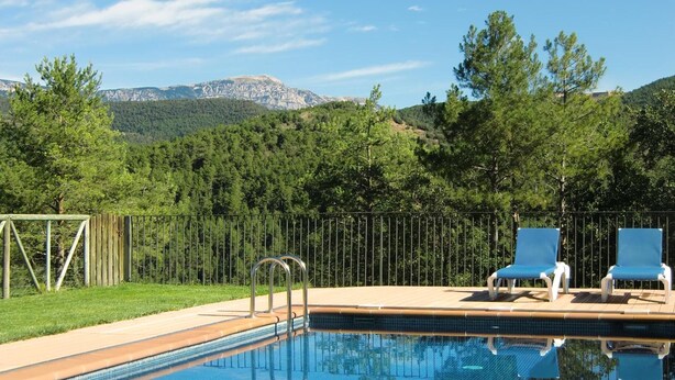 A swimming pool with lounge chairs, a metal ladder, and a view of a forested mountain range. - Casa Rural La Moixella: Catalan Country House with Private Pool and Pyrenees Views (Lladurs)