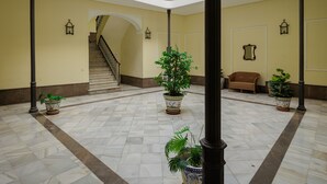 A spacious lobby with a marble floor, a staircase, potted plants, and a bench. - Gavidia Center Premium Suites Apartment with Wi-Fi and Air Conditioning (Seville)