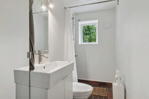 A modern bathroom with a white sink, mirror, and shower.