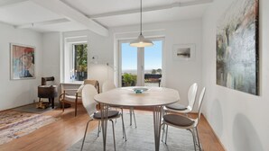 Een moderne eethoek met een ronde tafel, witte stoelen en uitzicht door grote ramen.