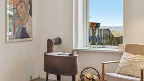 Een kamer met een rustieke kachel, een stoel met een decoratief kussen en een schilderij aan de muur.