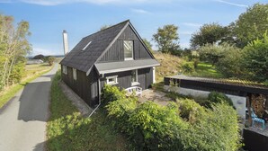 Een huis met een schuin dak, een veranda en een pad er naartoe.