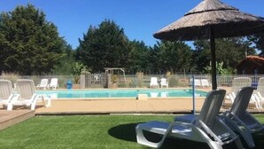 A swimming pool with lounge chairs and a thatched umbrella. - Chalet "Confort 12" with Terrace and Shared Pool (Saint-Gervais)