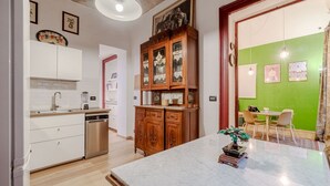 A kitchen with a dishwasher, wooden cabinets, a marble countertop, and a small bonsai tree.