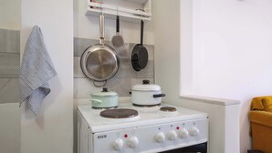 A kitchen with a white Esco stove, pots, and pans hanging above. - Artistic Bright Apartment – Attiki Metro by ΜΡS (Athina)