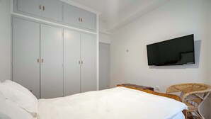 A bedroom with a bed, a wardrobe, a television, and a wicker chair. - Artistic Bright Apartment – Attiki Metro by ΜΡS (Athina)