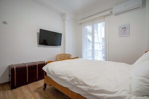 A bedroom with a bed, a television mounted on the wall, a suitcase, and a window with curtains. - Artistic Bright Apartment – Attiki Metro by ΜΡS (Athina)