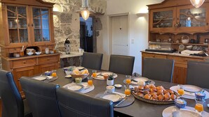A dining area with a stone wall, wooden cabinets, and a breakfast setting.
