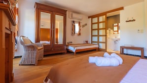 Hotelkamer met een bed, een stoel, een kledingkast, een spiegel en een badkamer door een geopende deur.