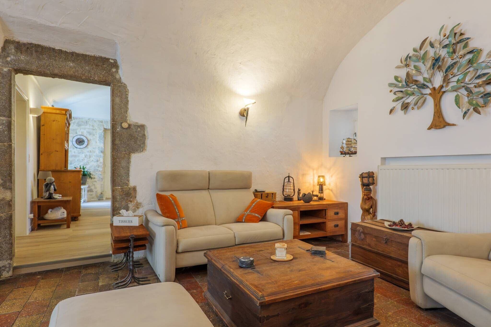 Ein gemütliches Wohnzimmer mit einer Couch, einem Couchtisch und einem dekorativen Baumgemälde an der Wand.
