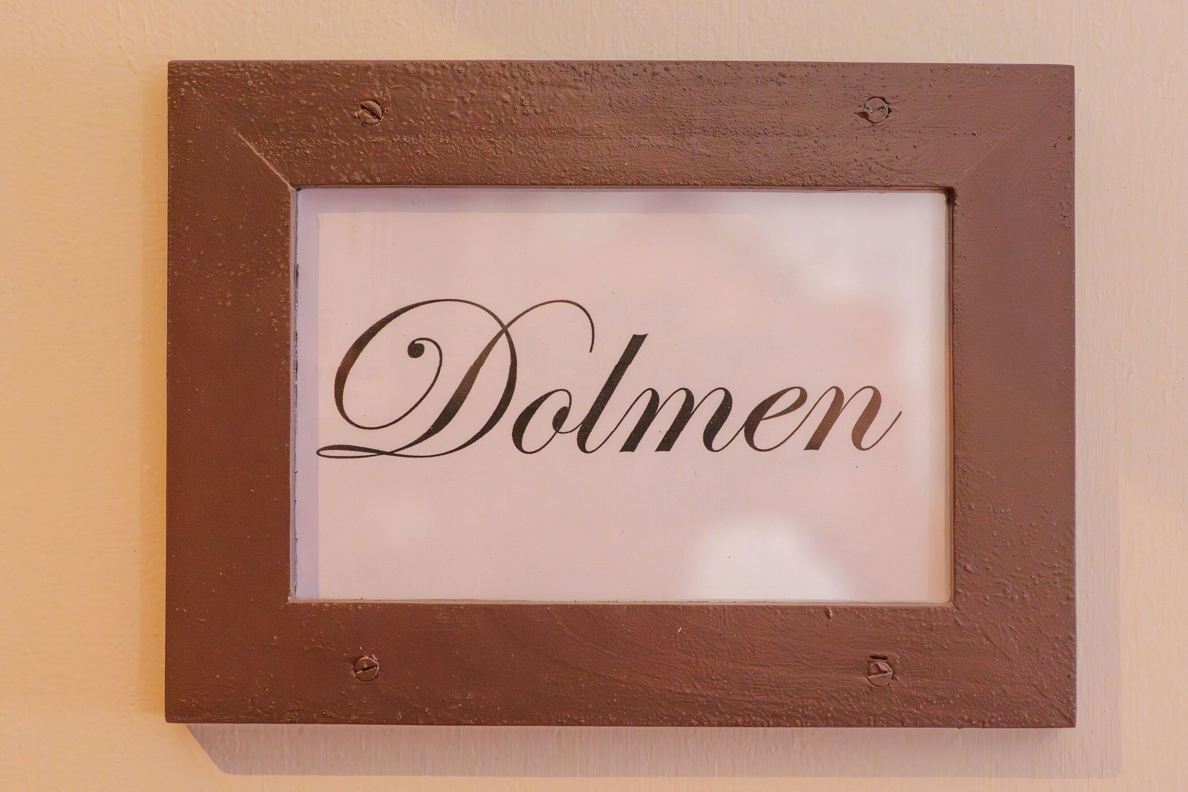 Un nom, « Dolmen », inscrit dans un cadre et accroché au mur.