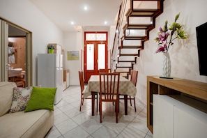 Een moderne keuken met een eetgedeelte, een trap en een woonkamer met een bank en een televisie.