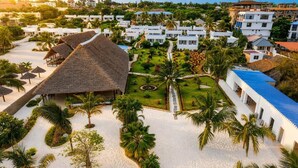 Un resort con edificios blancos, un jardín central y palmeras.