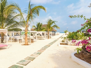 A beachside resort with thatched-roof cabanas, palm trees, and a clear view of the ocean. - Canary Kendwa Beach Resort (Kendwa)