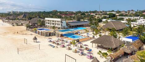 Ett hotell vid stranden med en swimmingpool, parasoller och solstolar.