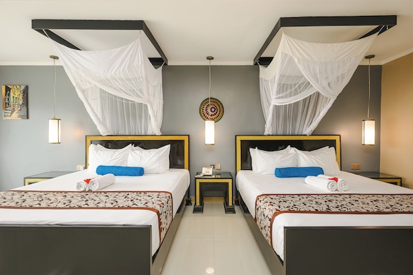 A hotel room with two beds, each with a canopy, a bedside table, a wall-mounted phone, and a decorative wall hanging. - Canary Kendwa Beach Resort (Kendwa)