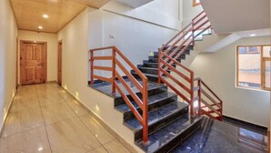 A modern staircase with wooden railings and a polished floor leading to an upper level. - OnlyStay Surya Mall Road Manali (Manali)