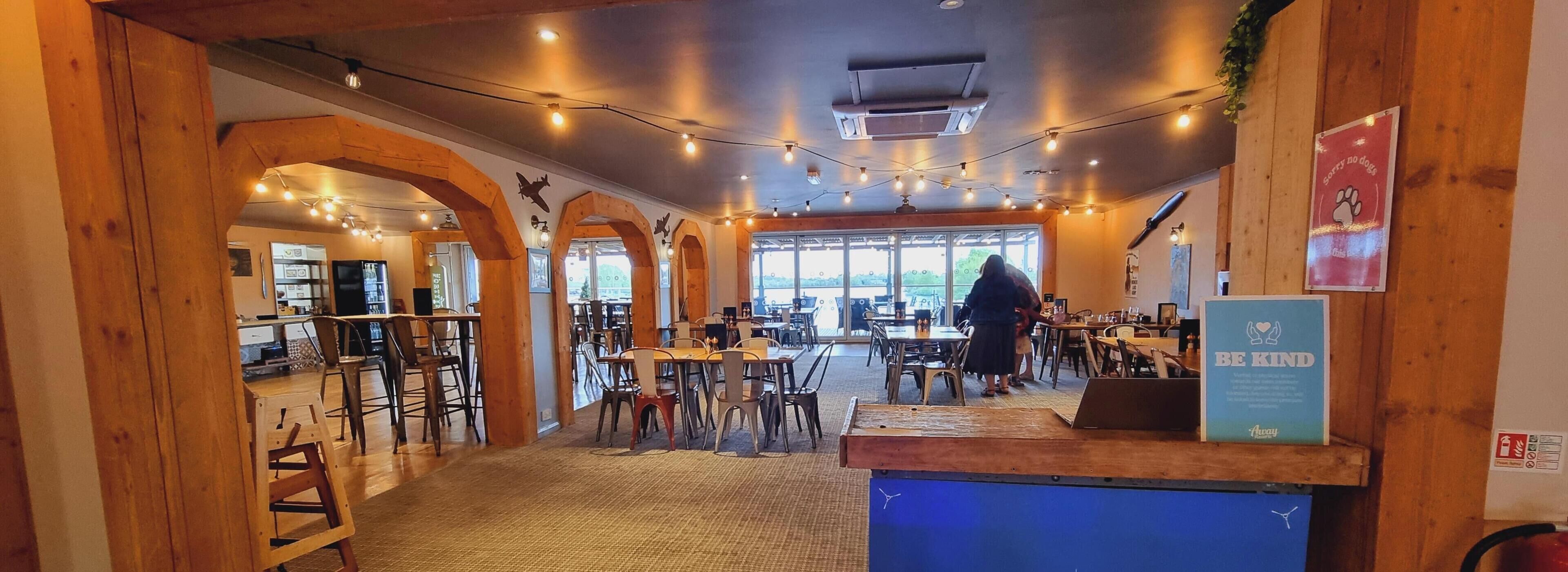 Ein Restaurant mit Holzbalken, Lichterketten und Blick ins Freie.