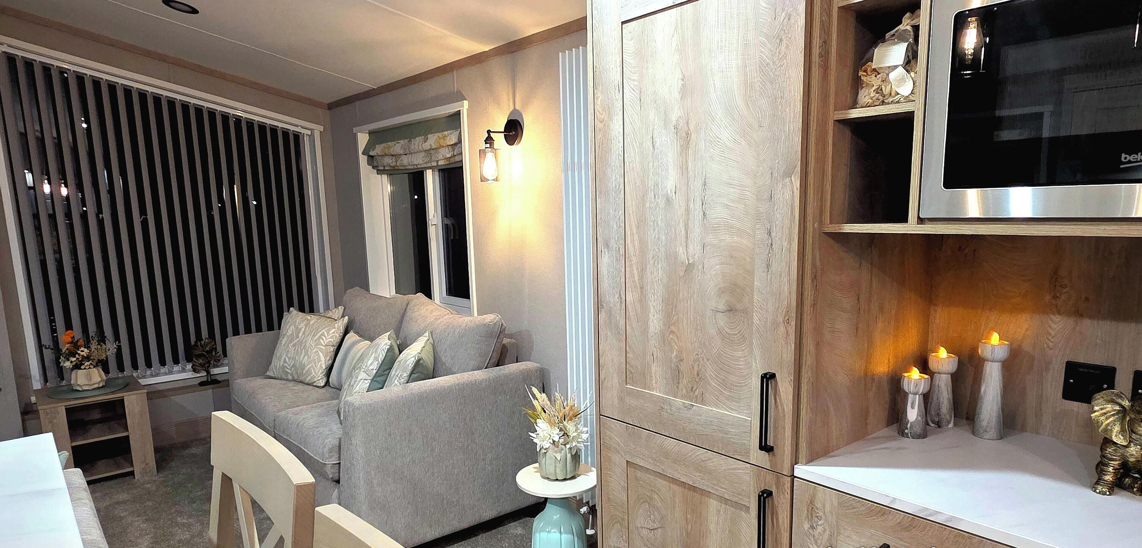 A modern living room with a grey sofa, wooden cabinets, and a built-in TV.