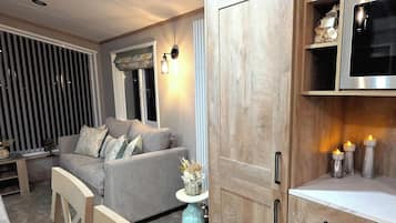 A modern living room with a grey sofa, wooden cabinets, and a built-in TV.