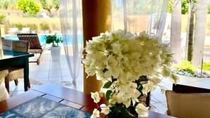 A room with a view of a pool, a table with a vase of flowers, and a chair. - Family Rooms with Sea View, Private Hot Tub, Wi-Fi and Air Conditioning (Marsala)