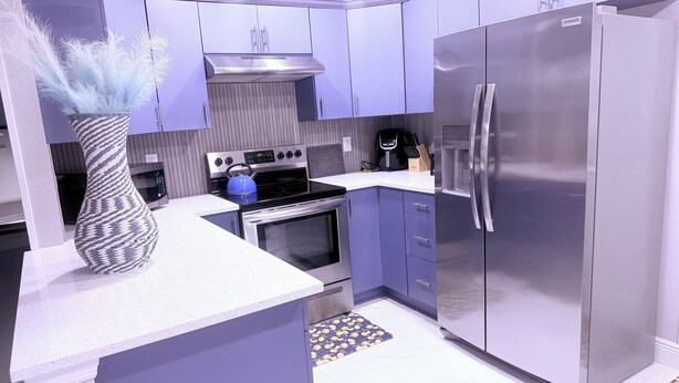 A modern kitchen with a stainless steel refrigerator, a built-in oven, and a gas stove.
