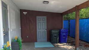 A covered entryway with a concrete floor, a grey door, and a blue mat.