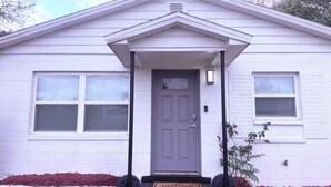 A house with a front door, two windows, a porch, and a welcome mat.