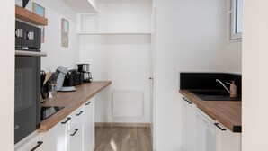 A compact kitchen with white cabinets, a wooden countertop, a built-in oven, and a coffee maker.