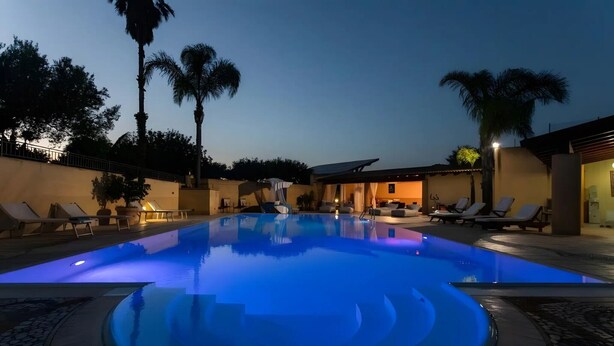 Une piscine avec des chaises longues et des palmiers.