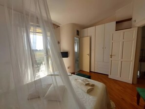 Una camera da letto con un letto, un armadio, una panca verde e una finestra con vista all'esterno.