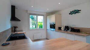 Una cocina moderna con un amplio ventanal, electrodomésticos integrados y encimera de madera.