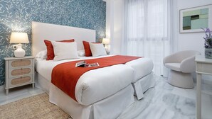 A neatly arranged hotel room with a large bed, white bedding, a red throw blanket, and a white nightstand with a lamp. - Genteel Home Uceda II (Cordoba)