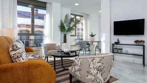 A modern living room with a sofa, armchair, and a dining area with a table and chairs. - Genteel Home Uceda III (Cordoba)
