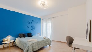 A bedroom with a bed, a desk, a chair, a lamp, and a window with curtains. - Apartment 'Araba Fenice' with Sea View, Wi-Fi and Air Conditioning (Marsala)
