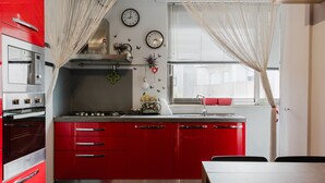A kitchen with red cabinets, a gas stove, a microwave, and a window with a view.