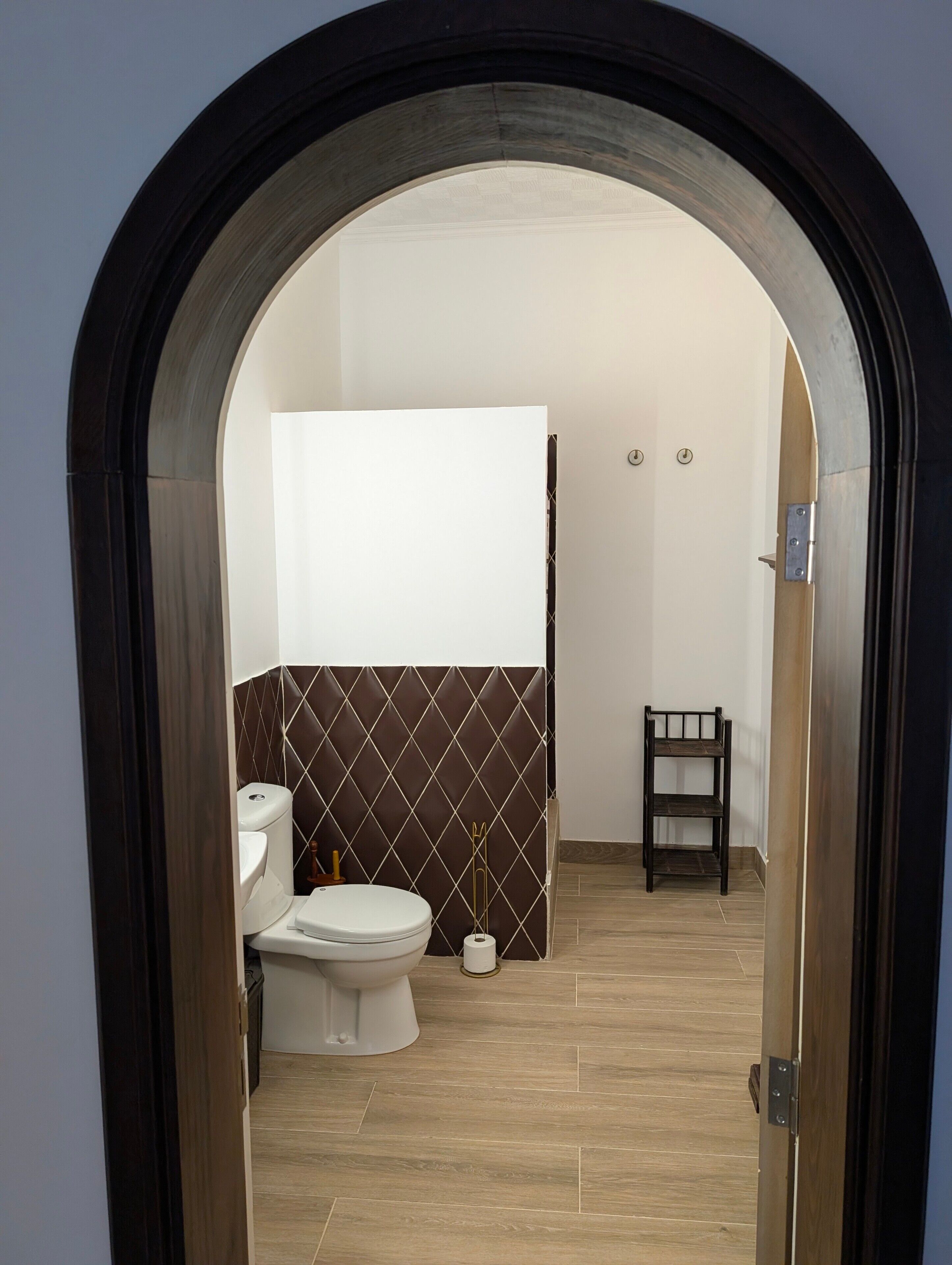 Un baño con inodoro, cortina de ducha y una silla de madera.