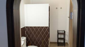 Un baño con inodoro, cortina de ducha y una silla de madera.