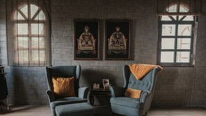 Una habitación con dos sillones, una mesita y dos cuadros enmarcados en la pared.