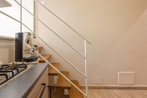 A kitchen with a gas stove, a coffee machine, and a wooden bench. - La Casetta Normanna Elisa Apartment – Central, Peaceful Retreat (palermo)