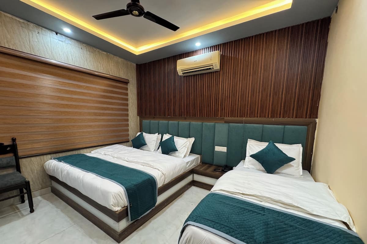 A hotel room with two beds, a ceiling fan, recessed lighting, an air conditioning unit, and a wooden panel wall.