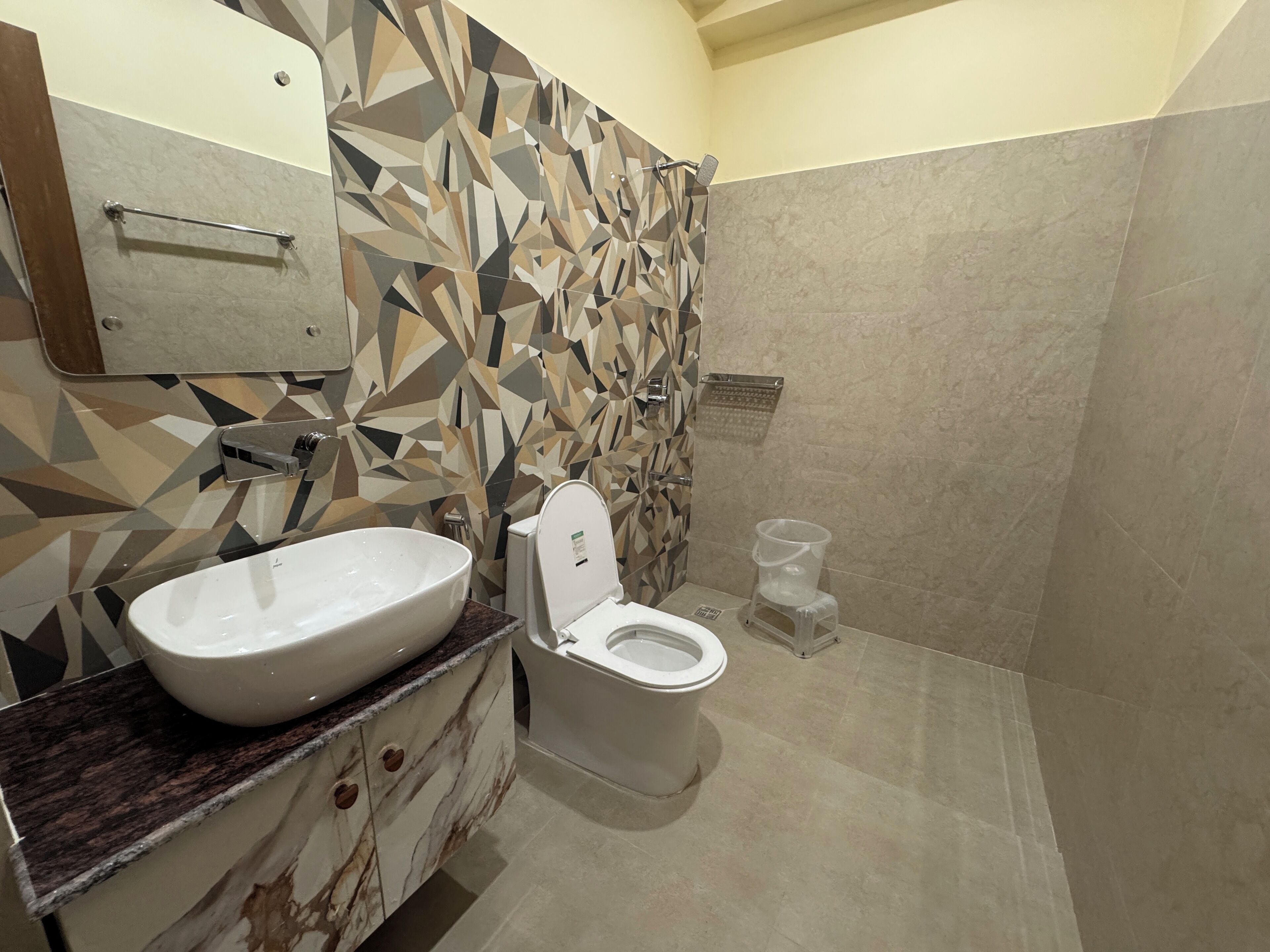 A modern bathroom with a geometric tile backsplash, a large white sink, and a toilet.